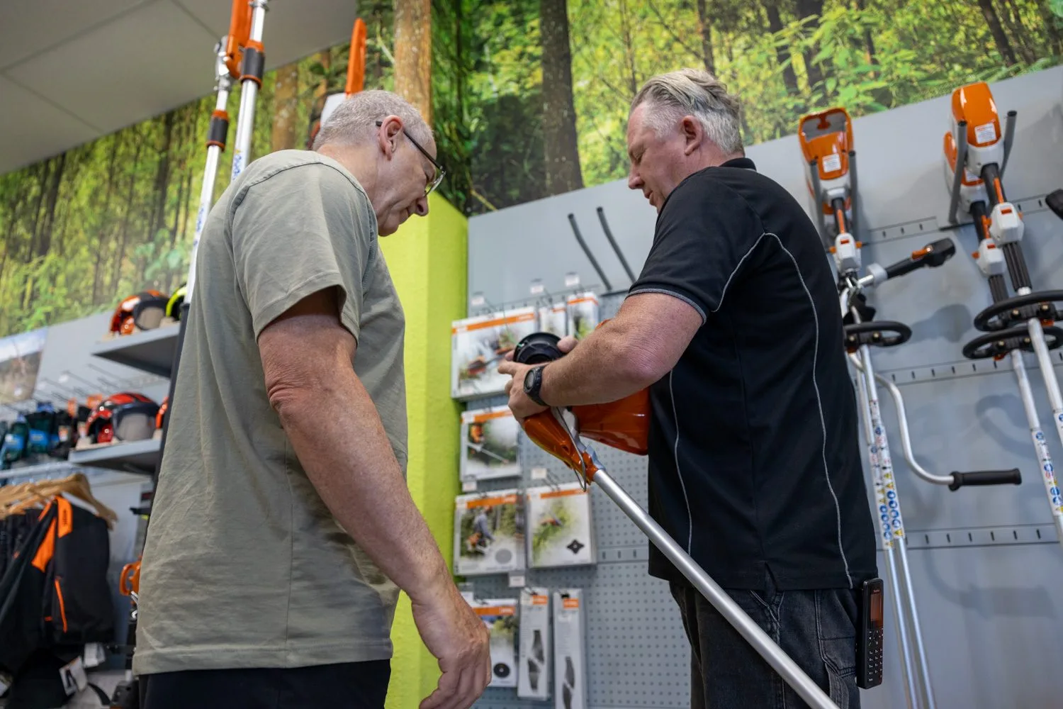 A team member demonstrating a long-reach STIHL tool to a customer in the showroom