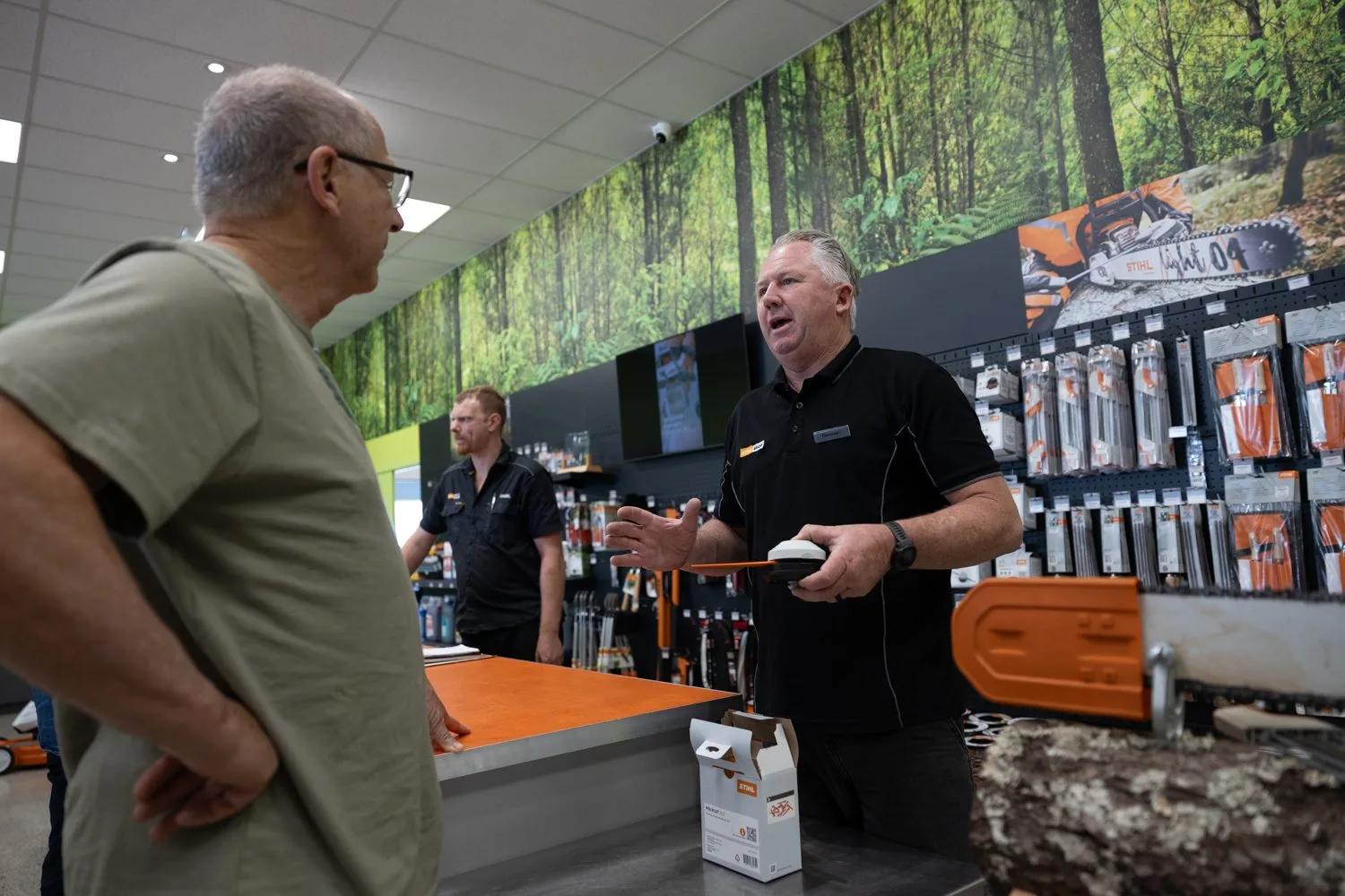 A STIHL SHOP Mt Maunganui team member talking a customer through a chainsaw at the counter