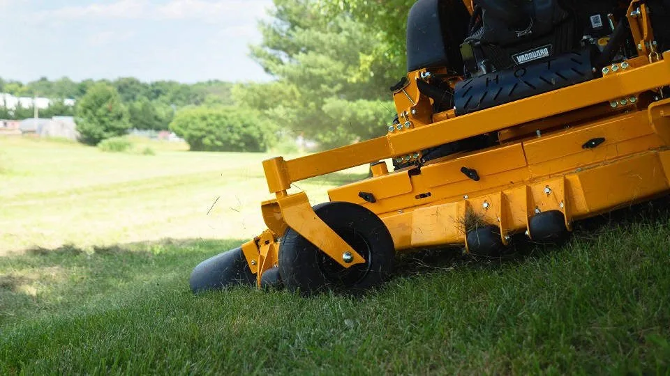 A Wright stand-on commercial mower cutting grass on a slope