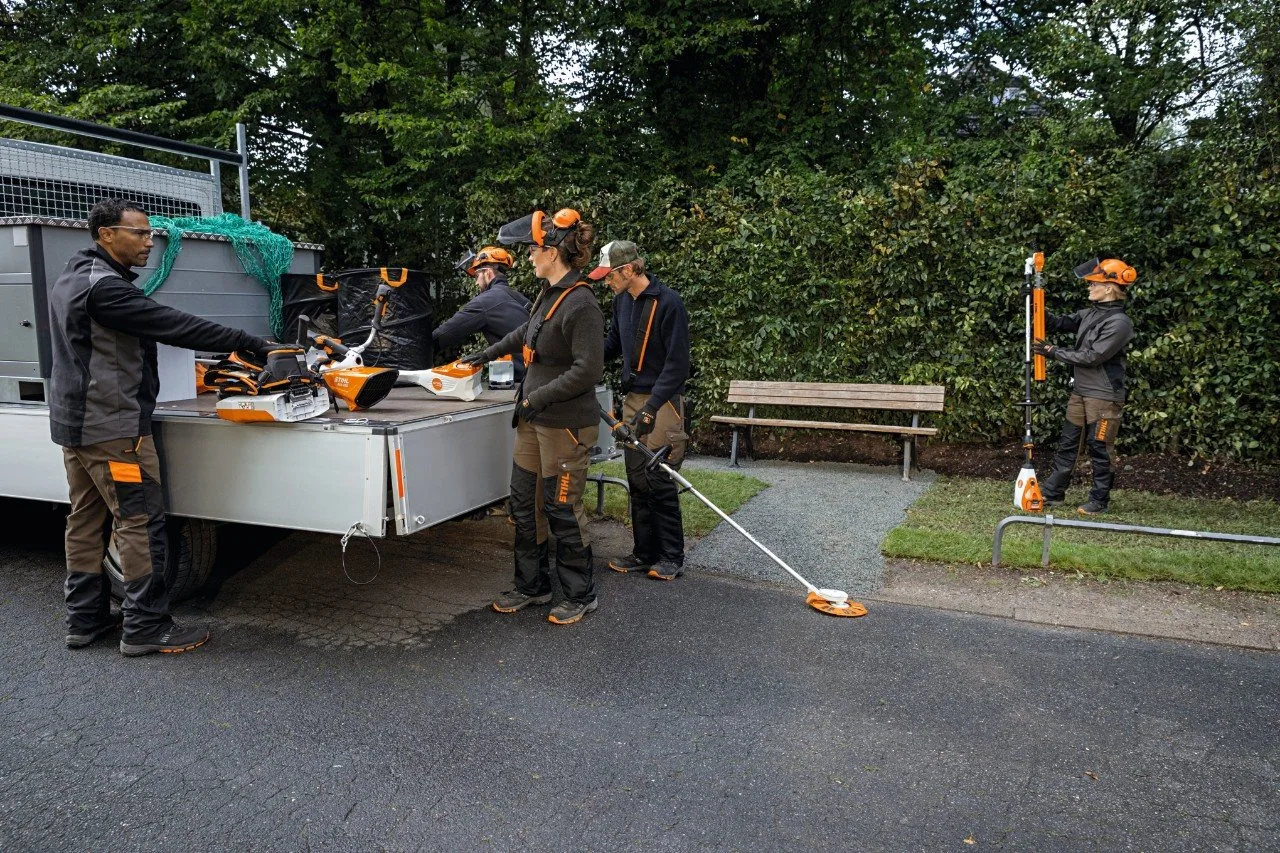 A landscaping crew unloading STIHL AP battery tools and a backpack battery from their work vehicle