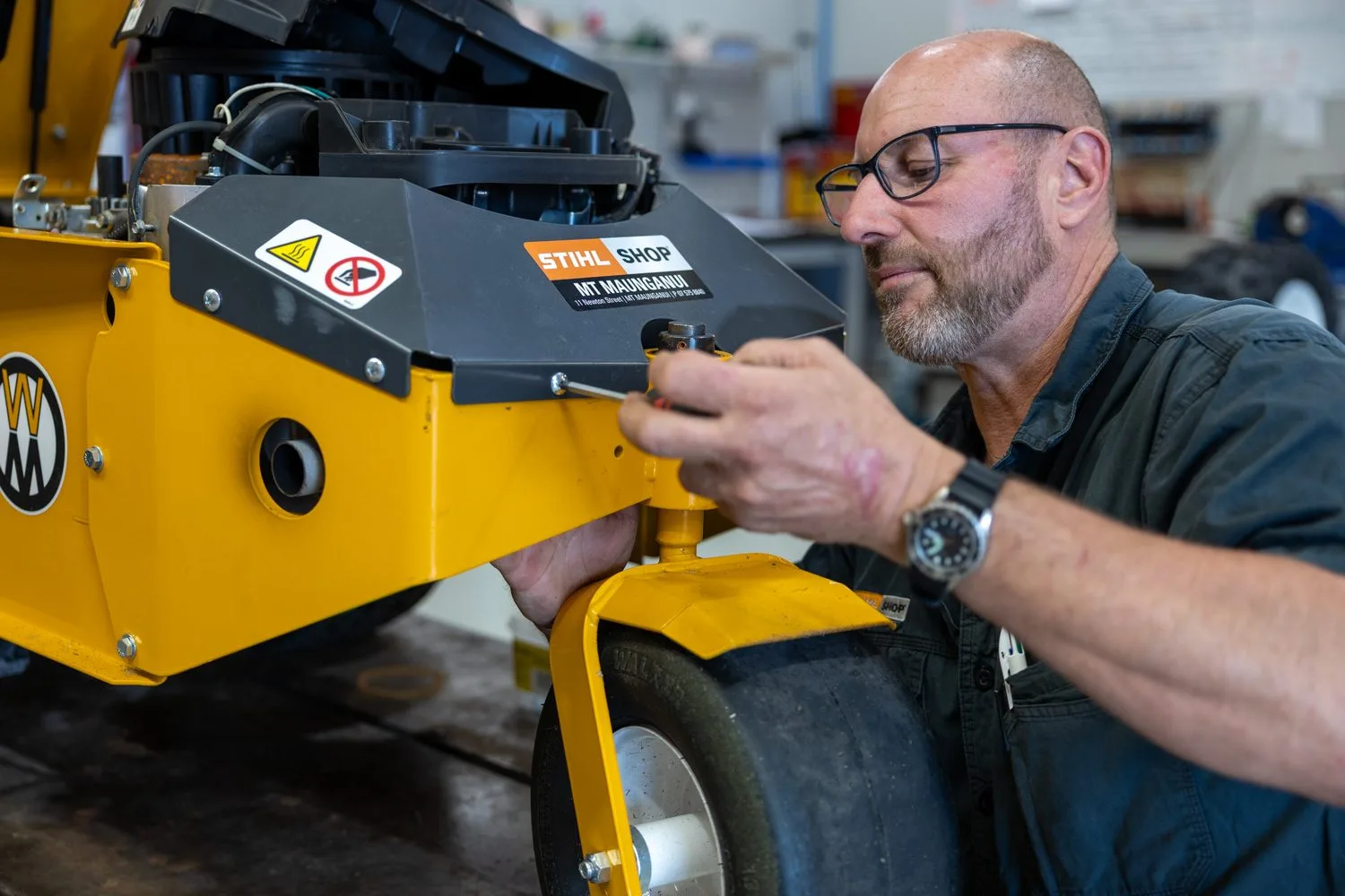 A technician servicing a Walker commercial mower in the STIHL SHOP Mt Maunganui workshop